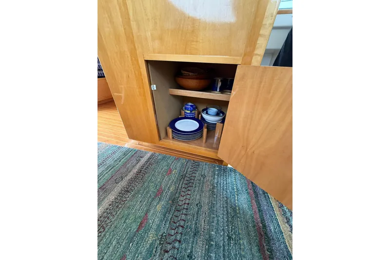 Slide: The Image of Open wooden cabinet with dishes inside on Norris Custom Motor Catamaran 41.4, 2002 model. - 74