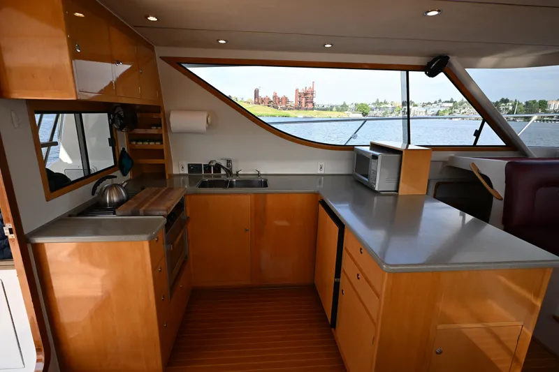 Slide: The Image of Modern kitchen interior on 2002 Roger Hill Power Cat 41.4 yacht, featuring wood cabinetry and waterfront view. - 75