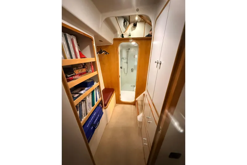 Slide: The Image of Norris Custom Motor Catamaran 41.4 interior, featuring a cozy hallway with bookshelves and a shower. - 93