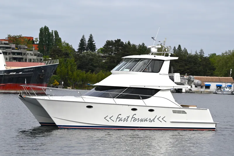 Slide: The Image of 2002 Roger Hill Power Cat 41.4 yacht "Fast Forward" on calm water, surrounded by greenery. - 108