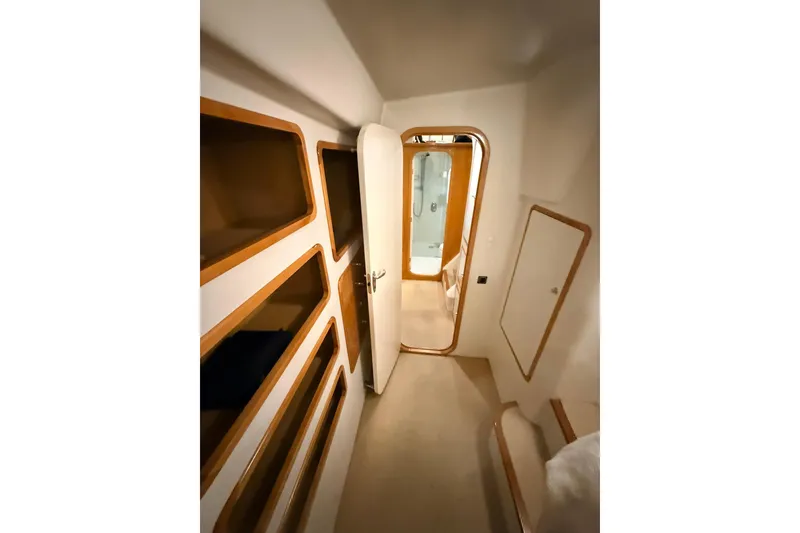 Slide: The Image of Interior of 2002 Norris Custom Motor Catamaran 41.4, featuring sleek wood-trimmed storage and doorway. - 86