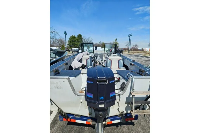 Slide: The Image of 1987 Blue Fin S170 boat with outboard motor, parked outdoors under clear blue sky. - 6