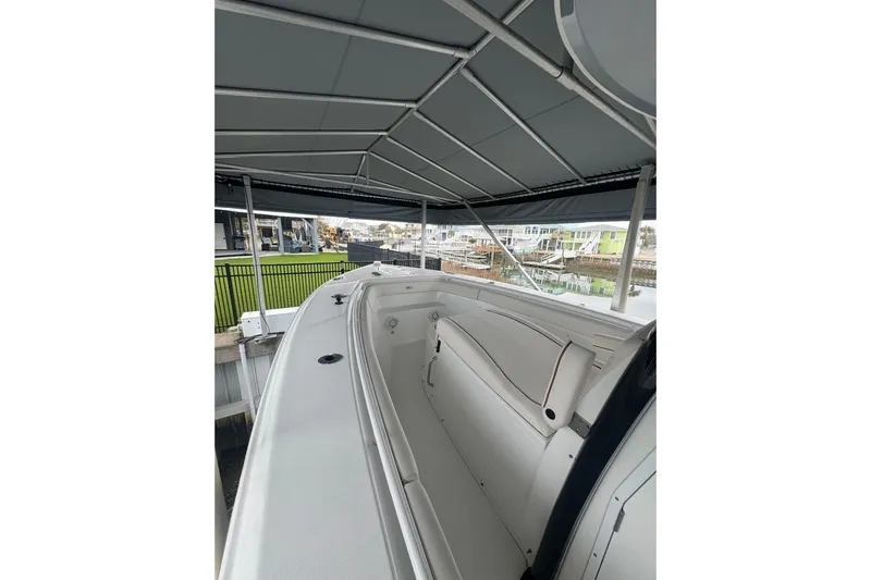 Slide: The Image of 2022 Sea Hunt Gamefish 27 Coffin Box boat under canopy, docked near waterfront homes. - 7