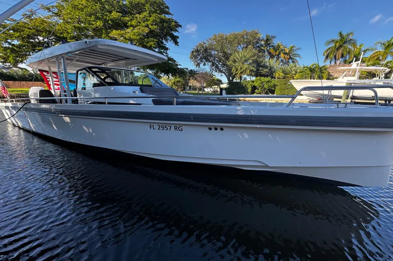 The Image of 2017 Axopar 37 Sun Top boat docked on calm water, surrounded by lush greenery. - 0
