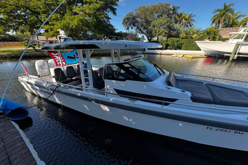 Slide: The Image of 2017 Axopar 37 Sun Top boat docked on a sunny day, surrounded by lush greenery. - 3