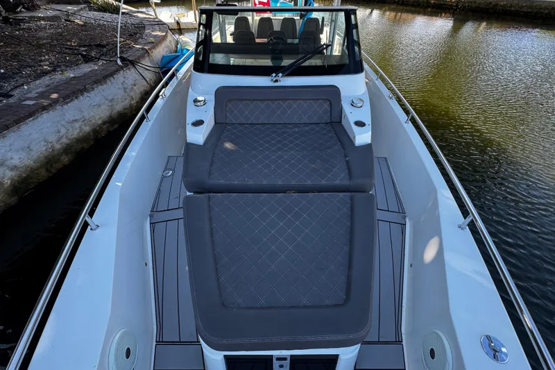 Slide: The Image of 2017 Axopar 37 Sun Top boat with cushioned seating on deck, docked by the water. - 34