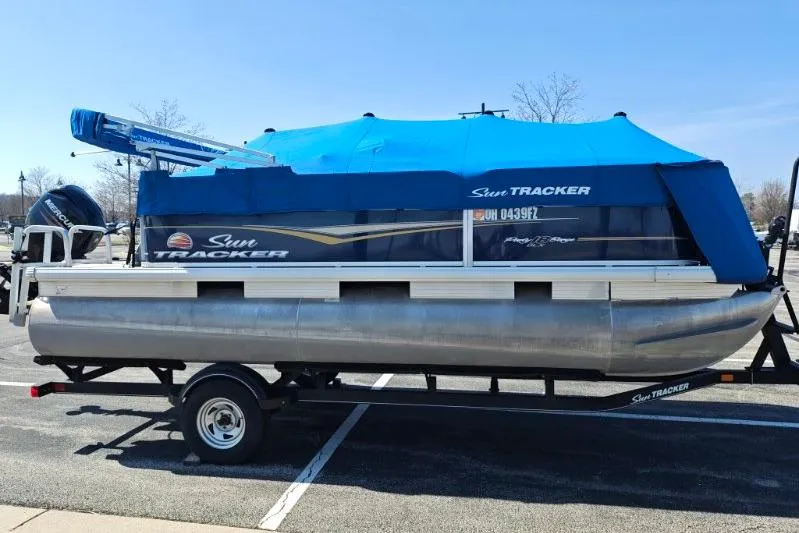 Slide: The Image of 2020 SUNTRACKER pb18 pontoon boat with blue cover on trailer. - 18