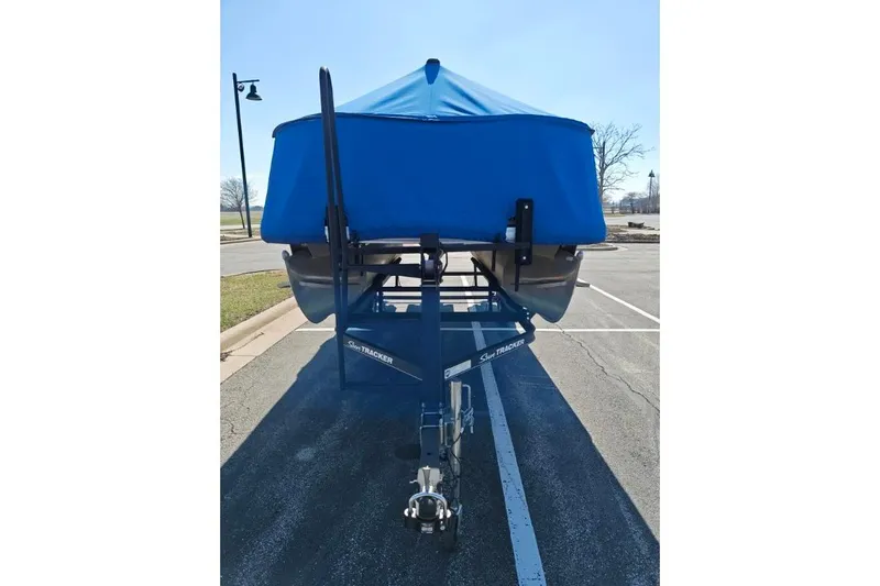 Slide: The Image of 2020 SUNTRACKER pb18 boat with blue cover on trailer in parking lot. - 19