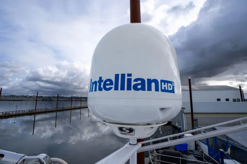 Slide: The Image of Intellian HD² satellite dome on 1965 De Vries Lentsch 64 Motoryacht, cloudy waterfront view. - 118