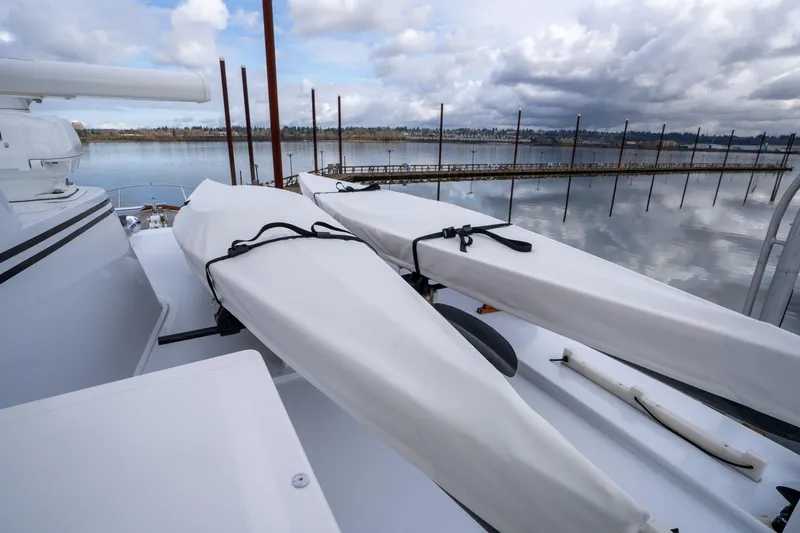 Slide: The Image of De Vries Lentsch 64 Motoryacht deck with covered equipment, serene waterfront view. - 79