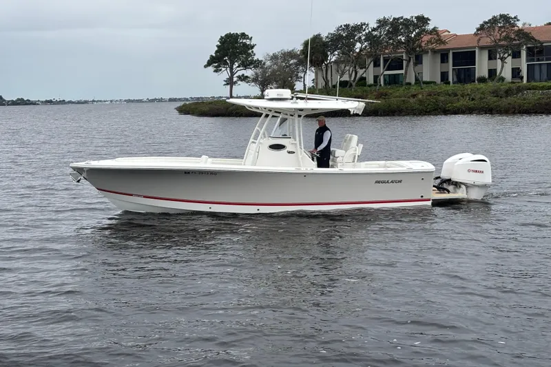 The Image of 2017 Regulator 28 boat on water with Yamaha engine, near shoreline and trees. - 0