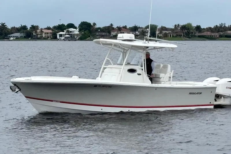 Slide: The Image of 2017 Regulator 28 boat on calm water, featuring a sleek white design and twin Yamaha engines. - 1