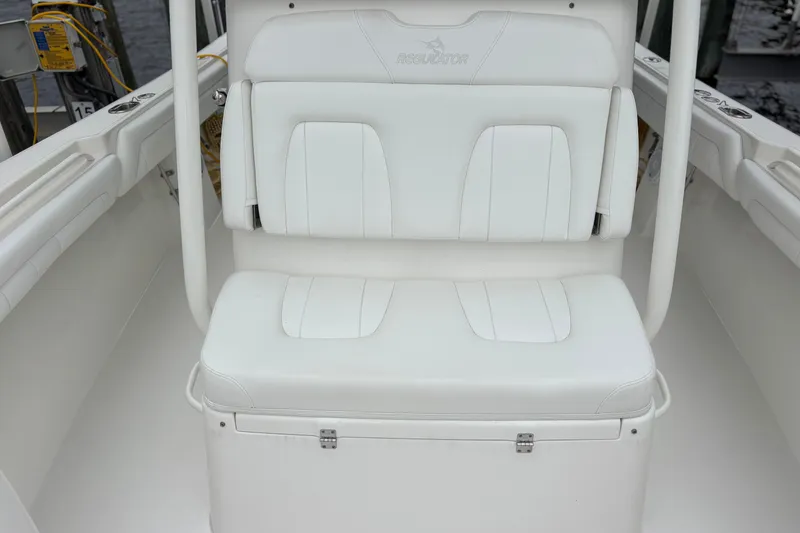 Slide: The Image of 2017 Regulator 28 boat interior with white cushioned seating and storage compartment. - 17