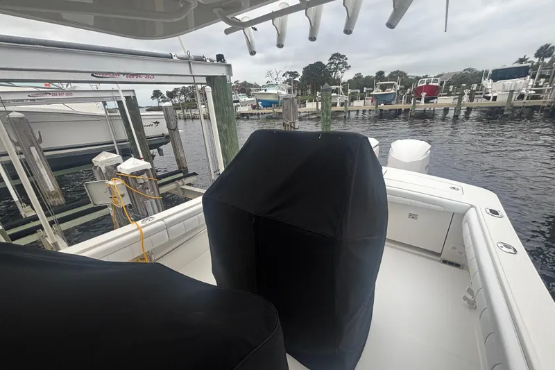 Slide: The Image of 2017 Regulator 28 boat docked, covered seats, marina background, overcast sky. - 19