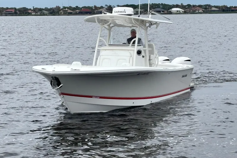 Slide: The Image of 2017 Regulator 28 boat cruising on a calm lake with a person at the helm. - 2