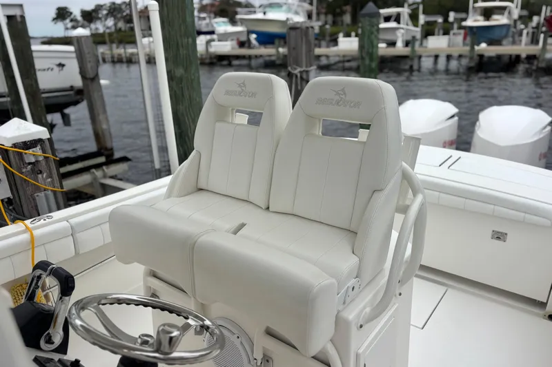 Slide: The Image of 2017 Regulator 28 boat helm with dual white cushioned seats at dock. - 21