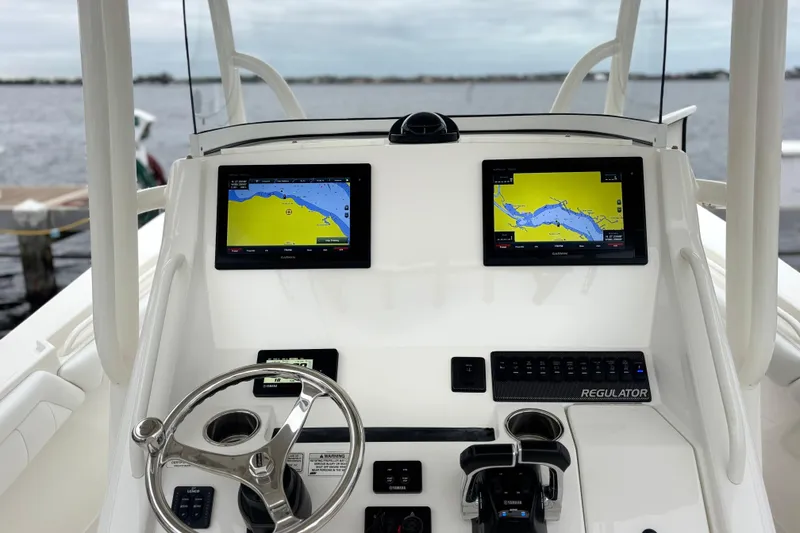 Slide: The Image of 2017 Regulator 28 boat dashboard with dual Garmin navigation screens and steering wheel. - 30