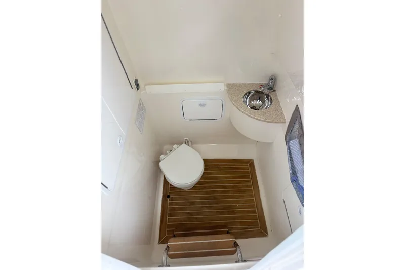 Slide: The Image of 2017 Regulator 28 boat bathroom with toilet, sink, and wooden floor. - 42