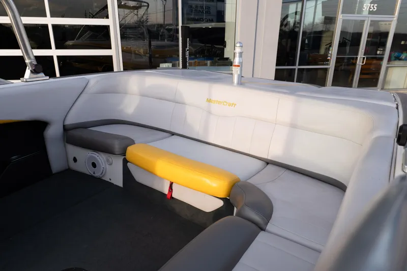 Slide: The Image of 2005 MasterCraft X10 boat interior with white and yellow seating, docked near a building. - 17
