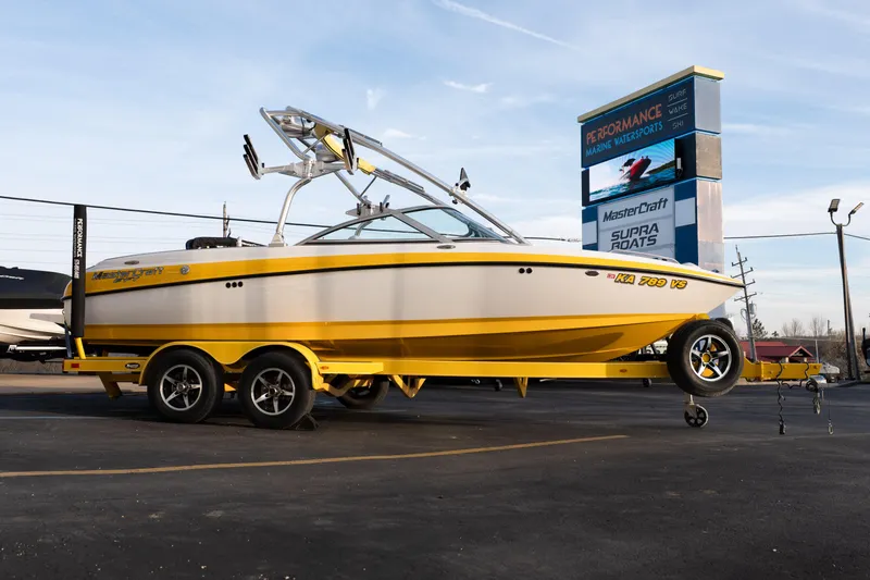 Slide: The Image of 2005 MasterCraft X10 boat on trailer at dealership, yellow and white design. - 8