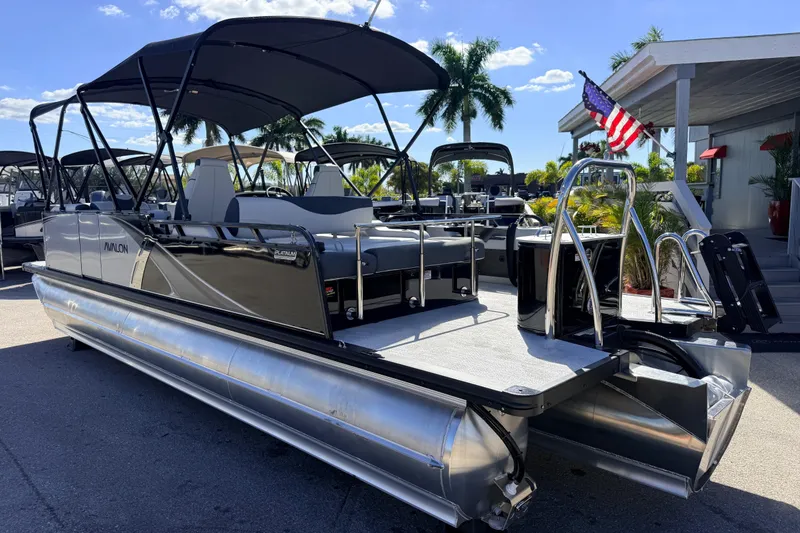 Slide: The Image of 2026 Avalon 2385 LSZ Versatile Rear Bench Tri Toon boat, parked outdoors under sunny skies. - 10