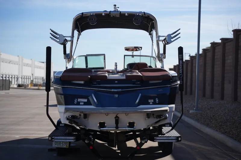 Slide: The Image of 2019 MasterCraft XT22 boat, rear view, parked outdoors on a sunny day. - 10