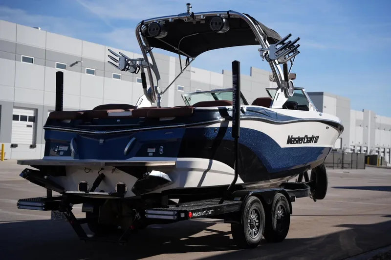 Slide: The Image of 2019 MasterCraft XT22 boat on trailer, parked near industrial buildings. - 11