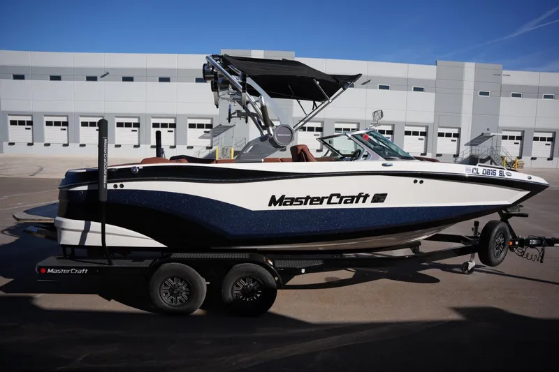 Slide: The Image of 2019 MasterCraft XT22 boat on trailer, parked outside industrial building. - 12