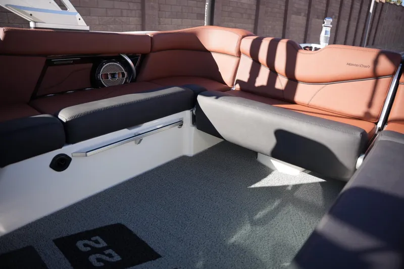 Slide: The Image of 2019 MasterCraft XT22 boat interior with brown and black seating, speaker, and carpeted floor. - 21