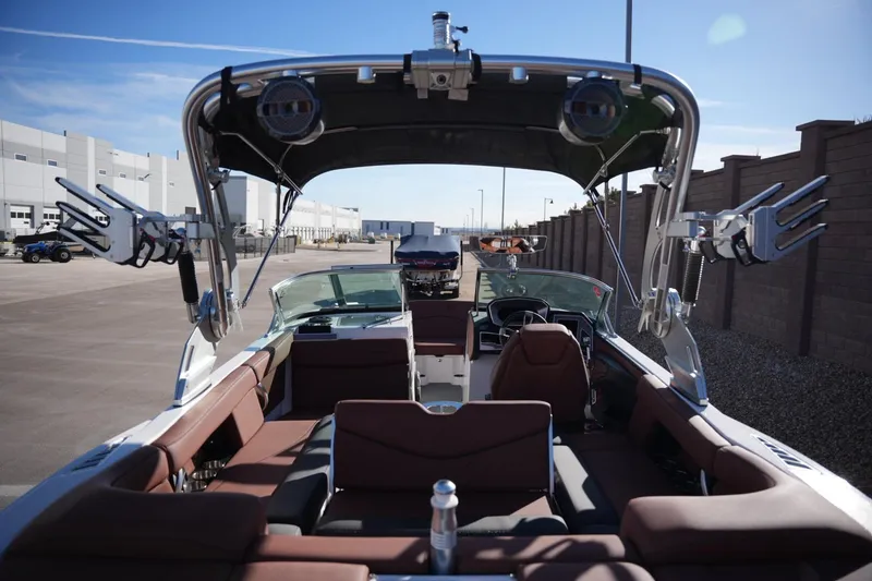 Slide: The Image of 2019 MasterCraft XT22 boat interior with seating and wakeboard racks, parked outdoors. - 26