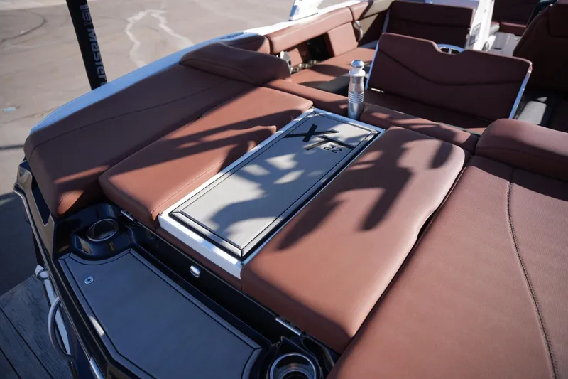 Slide: The Image of 2019 MasterCraft XT22 boat interior with brown seating and storage compartment. - 27