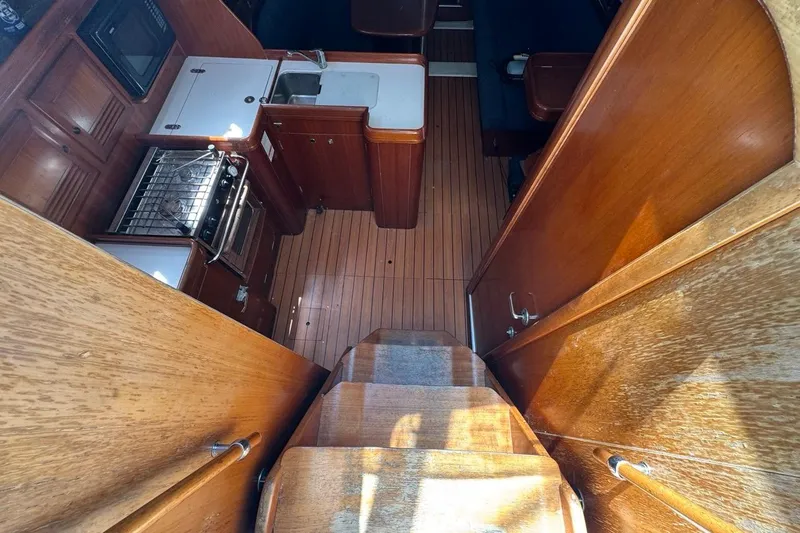 Slide: The Image of Interior view of 2005 Beneteau Oceanis Clipper 373 sailboat, featuring wooden cabinetry and compact kitchen. - 30