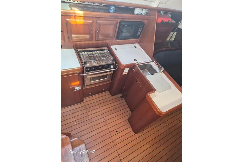 Slide: The Image of Galley of 2005 Beneteau Oceanis Clipper 373 with stove, sink, and wooden cabinetry. - 9
