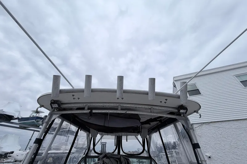 Slide: The Image of 1990 Grady-White Sailfish 25 Sportbridge boat with rod holders, under cloudy sky. - 7