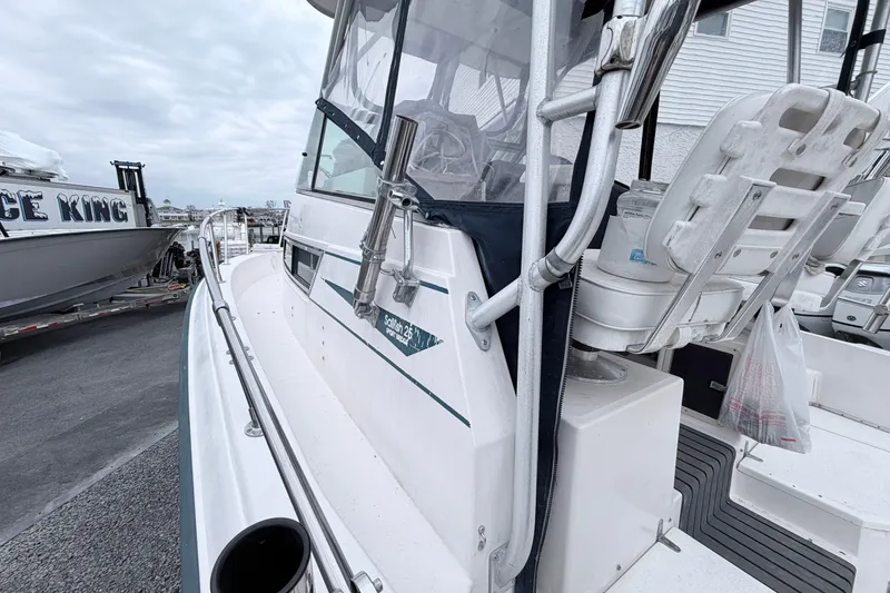Slide: The Image of 1990 Grady-White Sailfish 25 Sportbridge boat docked, showcasing side view and seating area. - 8