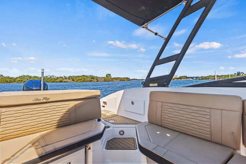 Slide: The Image of 2024 Sea Ray SPX 230 Outboard boat interior with tan seating, overlooking serene water. - 43