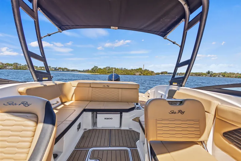 Slide: The Image of 2024 Sea Ray SPX 230 Outboard boat interior with tan seating and scenic water view. - 48