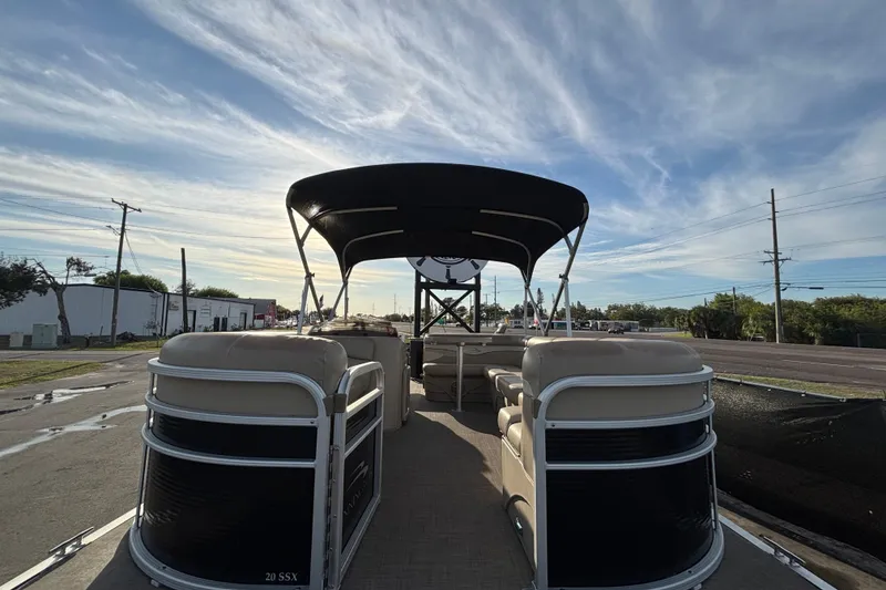 Slide: The Image of 2015 Bennington 20 SSX pontoon boat with canopy, parked under a partly cloudy sky. - 10