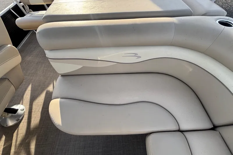 Slide: The Image of 2015 Bennington 20 SSX boat interior seating with beige upholstery and cup holder. - 47