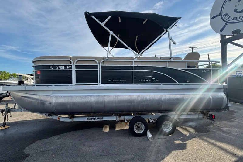 Slide: The Image of 2015 Bennington 20 SSX pontoon boat on trailer with canopy, parked outdoors. - 5