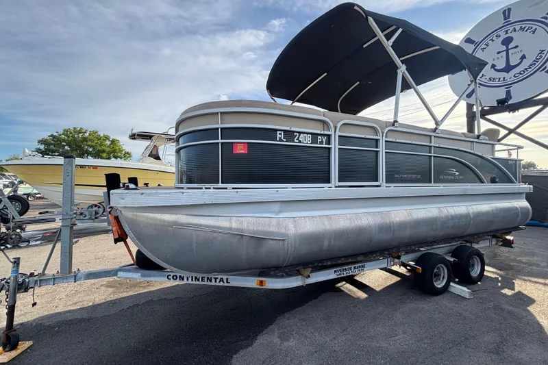 Slide: The Image of 2015 Bennington 20 SSX pontoon boat on trailer with canopy, parked outdoors. - 6