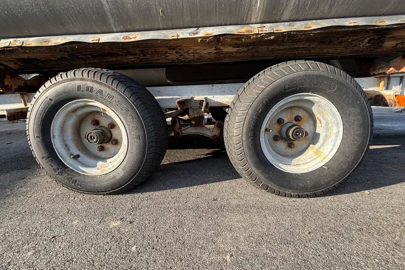 Slide: The Image of Rusty trailer wheels under a 2015 Bennington 20 SSX boat on asphalt. - 70