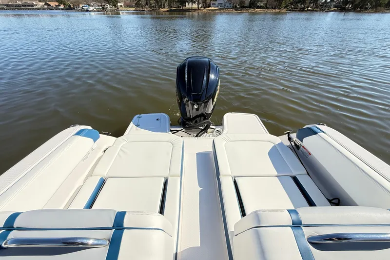 Slide: The Image of 2023 Chaparral 250 OSX boat with sleek seating and powerful outboard motor on a calm lake. - 10