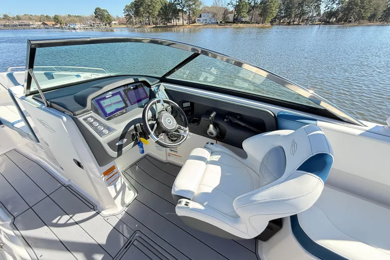Slide: The Image of 2023 Chaparral 250 OSX boat cockpit with modern steering and controls on a serene lake. - 12