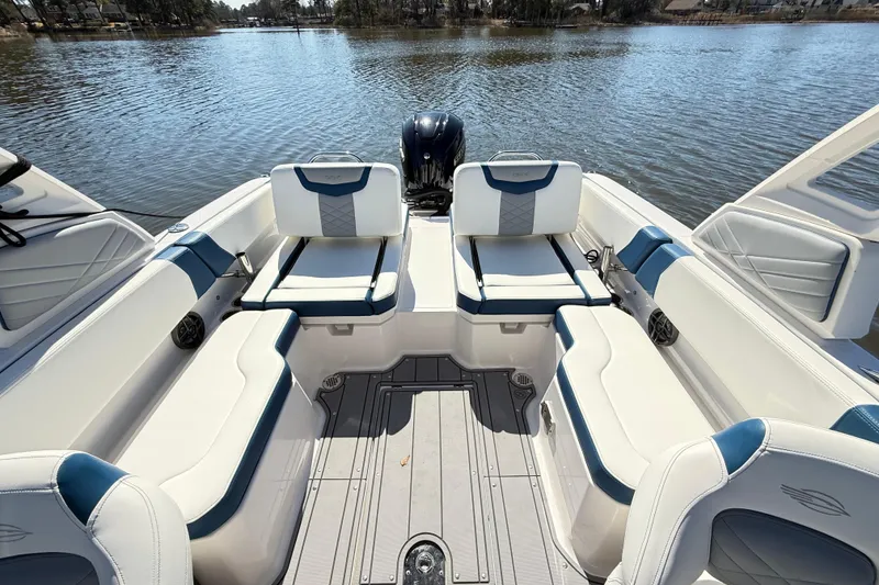 Slide: The Image of 2023 Chaparral 250 OSX boat interior with white and blue seating on a calm lake. - 16