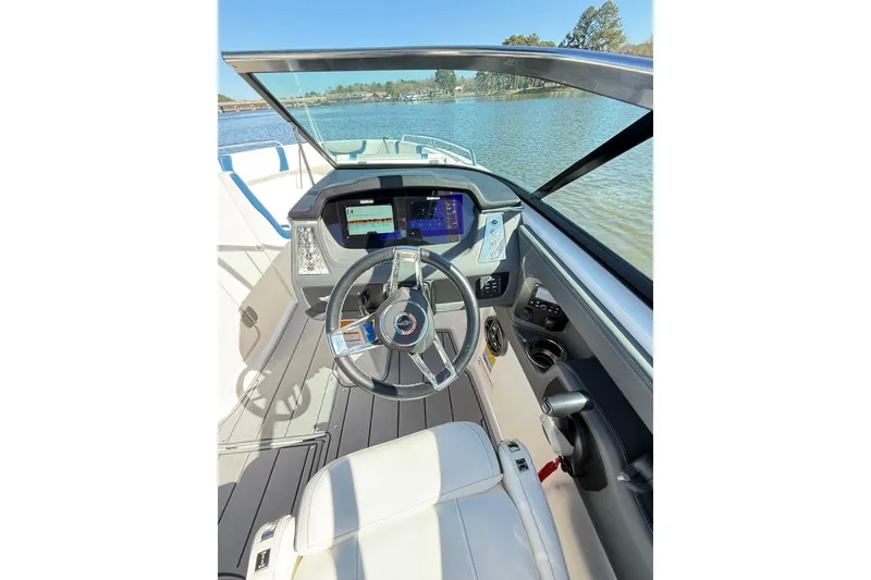 Slide: The Image of 2023 Chaparral 250 OSX boat cockpit with modern steering and digital display on a lake. - 19