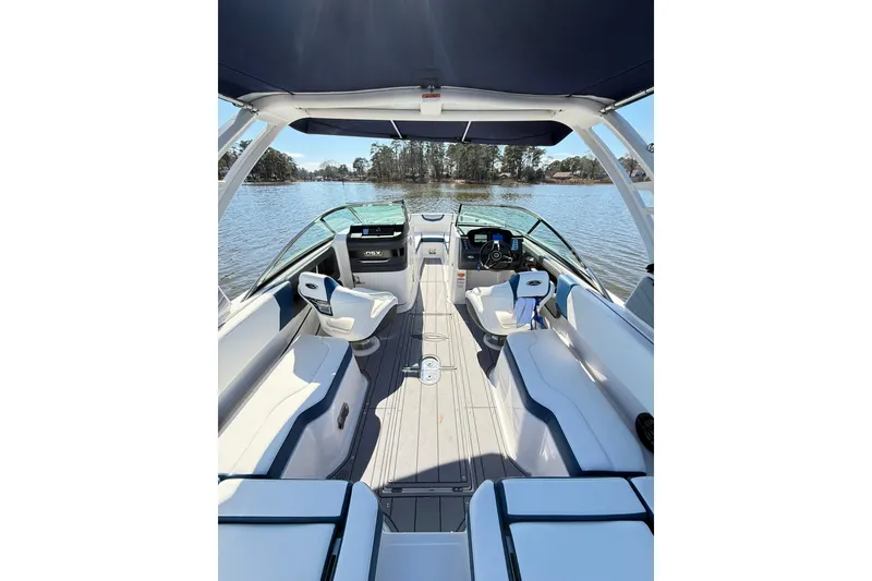 Slide: The Image of 2023 Chaparral 250 OSX boat interior with seating and steering, on a calm lake. - 22