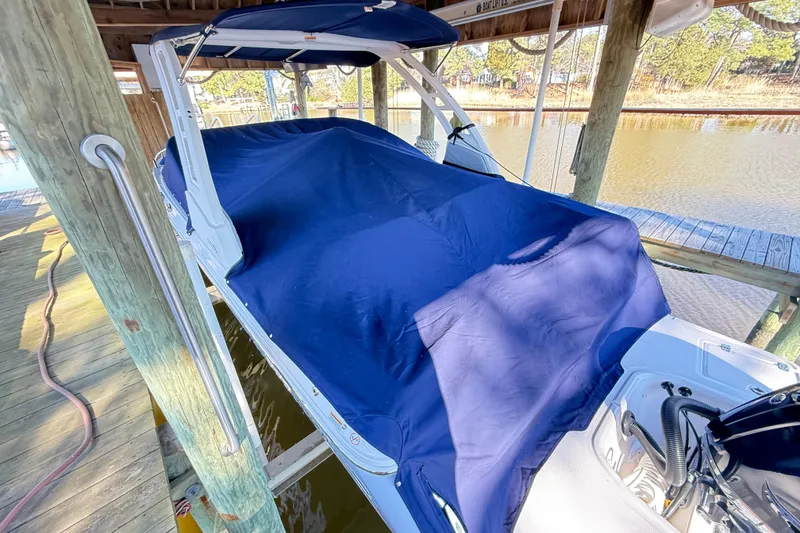 Slide: The Image of 2023 Chaparral 250 OSX boat covered with a blue tarp in a docked setting. - 27