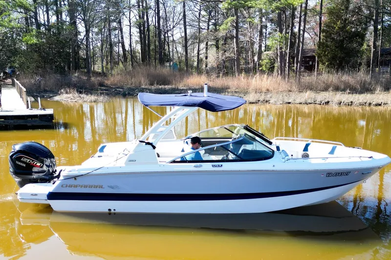 Slide: The Image of 2023 Chaparral 250 OSX boat on calm water, surrounded by trees. - 3
