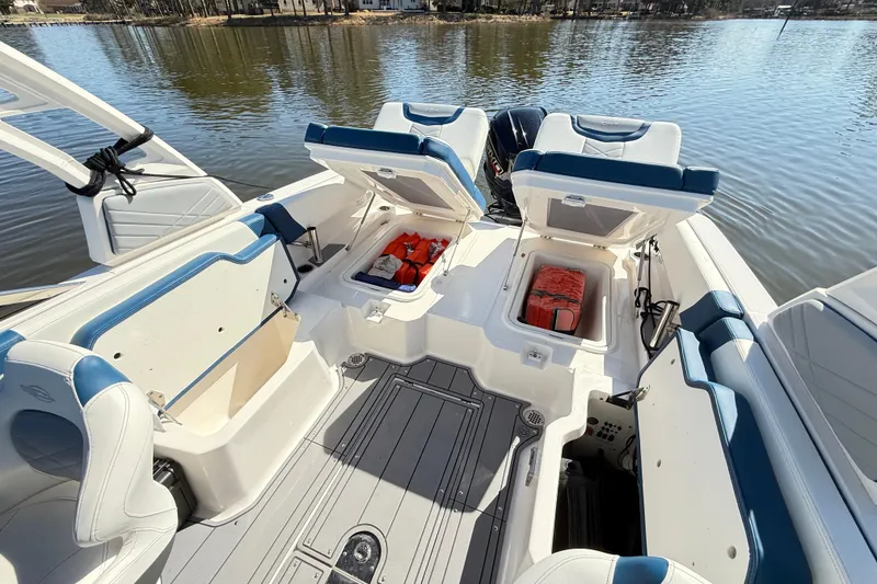 Slide: The Image of 2023 Chaparral 250 OSX boat interior with open storage compartments on a calm lake. - 31